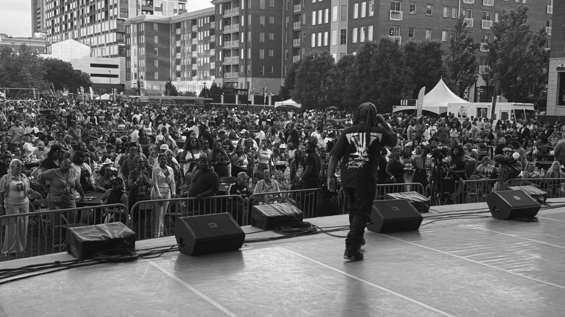 A performer on stage in front of a packed city crowd
